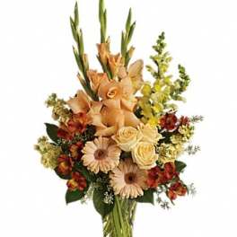Tall mixed bouquet in a clear glass vase with peach and cream flowers