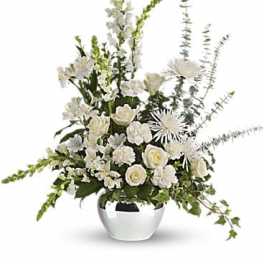 White floral arrangement in a silver vase with tall spires and trailing greenery