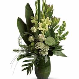 Green floral arrangement in a dark vase with tall stems and tropical leaves