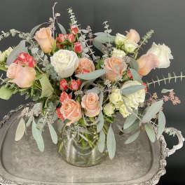 Mixed roses in a clear glass vase with airy eucalyptus on a silver tray