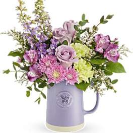 Lavender and pink flowers arranged in a purple pitcher vase