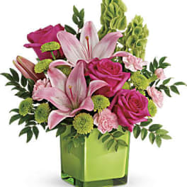 Pink lilies and roses in a green glass vase