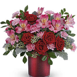 Red roses and pink flowers arranged in a red vase