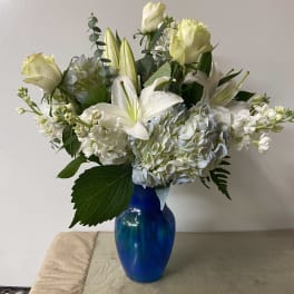 White roses and lilies arranged in a blue vase