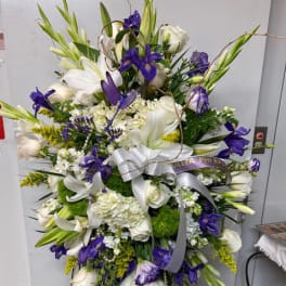 Large white and purple funeral spray on a stand with ribbon