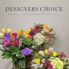 Three colorful mixed flower bouquets on stands against a plain wall