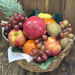 Fruit basket with apples, grapes, kiwi, oranges, and a pineapple