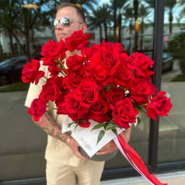 Large bouquet of red roses wrapped in white paper with a red ribbon
