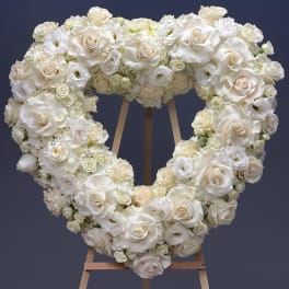 Heart-shaped white floral wreath on a wooden easel
