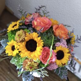 Bouquet of sunflowers and pink-orange roses with mixed filler flowers