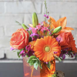 Orange roses and gerbera daisies in a glass vase
