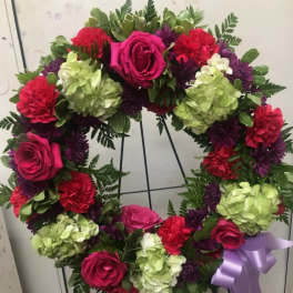 Heart-shaped floral wreath with pink roses, hydrangeas, and purple flowers