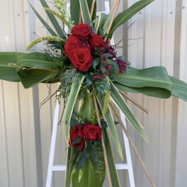 Tall standing floral spray with red roses and large tropical leaves