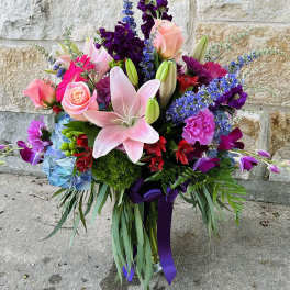 Colorful bouquet with pink lilies, roses, and purple flowers in a vase