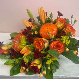 Orange roses and lilies arranged with decorative pumpkins
