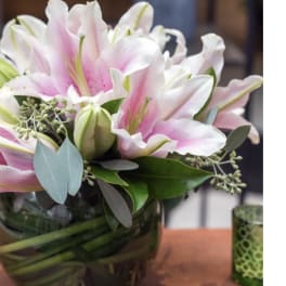 Pink and white lilies arranged in a glass vase