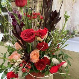 Tall floral arrangement with red and peach roses in a vase