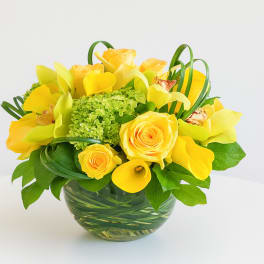 Yellow roses and calla lilies in a glass vase
