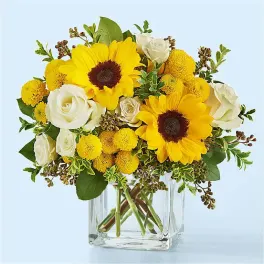 Yellow sunflowers and white roses in a clear glass vase