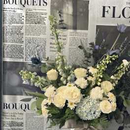 Cream and pale blue bouquet in a white vase with a burlap bow