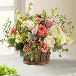 Mixed pink and white roses in a wooden basket with airy filler flowers