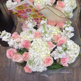 Two bouquets of pink roses and white flowers wrapped in clear paper