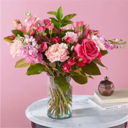 Pink bouquet of roses, carnations, and lilies in a glass vase