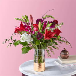 Mixed bouquet of red and purple flowers in a clear glass vase