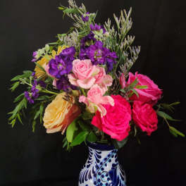 Mixed bouquet of pink, purple, and yellow flowers in a patterned vase