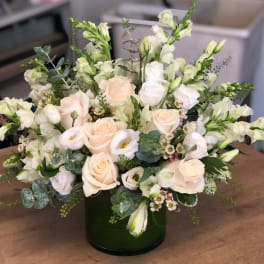 Cream roses and white blooms arranged in a dark green vase