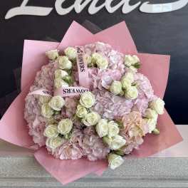 Pink bouquet of hydrangeas and white roses wrapped in pink paper