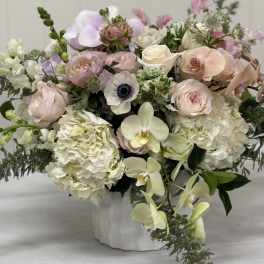 Pastel bouquet with roses, hydrangeas, orchids, and anemones in a white vase