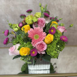 Mixed bouquet with pink and yellow roses, pink gerbera daisy, and green hydrangeas in a vase