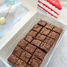 Box of chocolate brownies cut into squares with a cake slice nearby