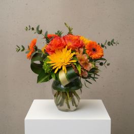 Orange and yellow mixed bouquet in a clear glass vase