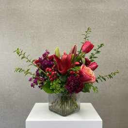 Mixed bouquet of red and pink flowers in a clear glass vase