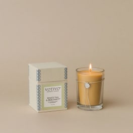Lit candle in a glass holder beside its box