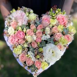 Heart-shaped arrangement of pink and cream roses with white blooms and berries