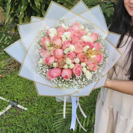 Bouquet of pink and white roses wrapped in white paper