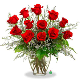 Arrangement of red roses with delicate filler flowers in a clear glass vase