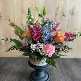 Colorful mixed flower arrangement in a pedestal vase