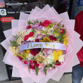 Large mixed flower bouquet wrapped in pink paper with an "I Love You" ribbon