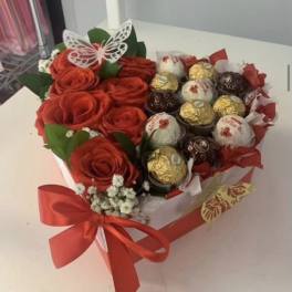 Heart-shaped bouquet of red roses and assorted chocolates with a red ribbon