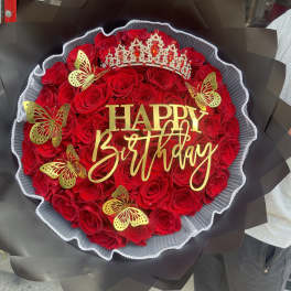 Red rose bouquet with a birthday sign, crown, and gold butterfly accents