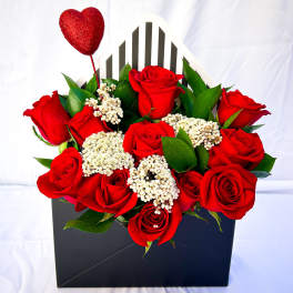 Red roses in a black gift box with a glittery heart pick