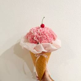 Pink carnation bouquet in a waffle cone with a cherry topper