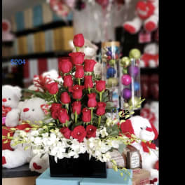 Red roses arranged in a black box with white orchids at the base