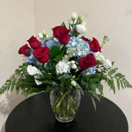 Red roses and blue hydrangeas in a clear glass vase