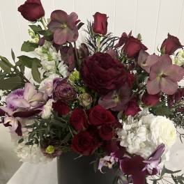 Deep burgundy and white floral arrangement in a black vase