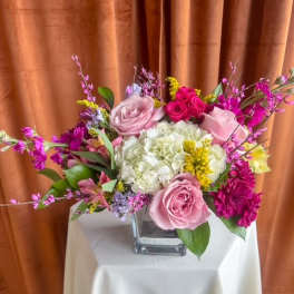 Pink and white rose arrangement in a square glass vase